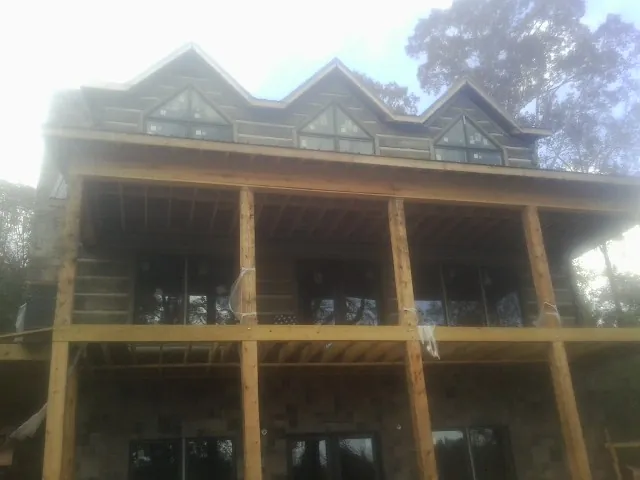Dormers and porch framing on a large log home under construction — Roof Coating work by our crew in Jaffrey