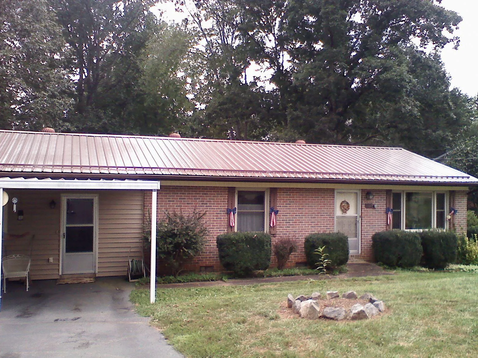 Bronze metal roof and carport on a brick ranch home — Roof Repair work by our crew in Jaffrey