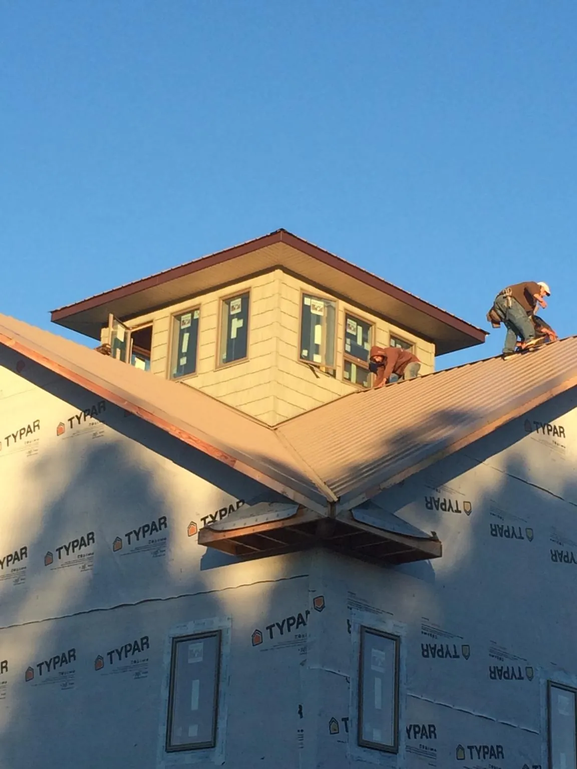 Roofers working around a rooftop cupola on a new metal roof at sunset — Roof Waterproofing in Jaffrey by Roofing Brothers
